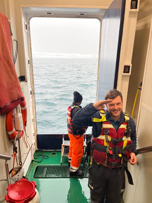 Maritime crew boards vessel in survival gear during snowstorm