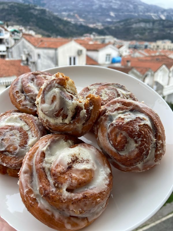 Tourist enjoys cinnamon roll breakfast with scenic views in Budva