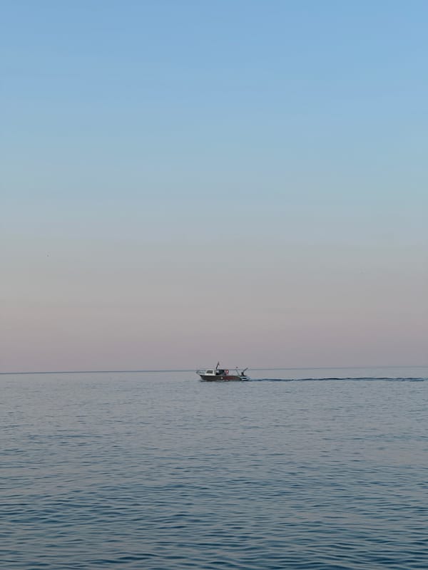 Dawn on the Montenegrin coast — boat on still water, tide pools below