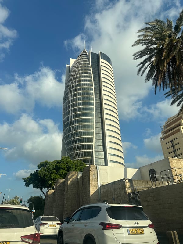 Haifa streets: glass tower, palm-lined boulevard, rainbow flag