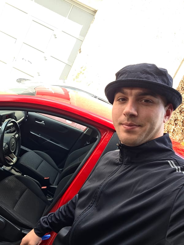 Young man in black hat observed with red car
