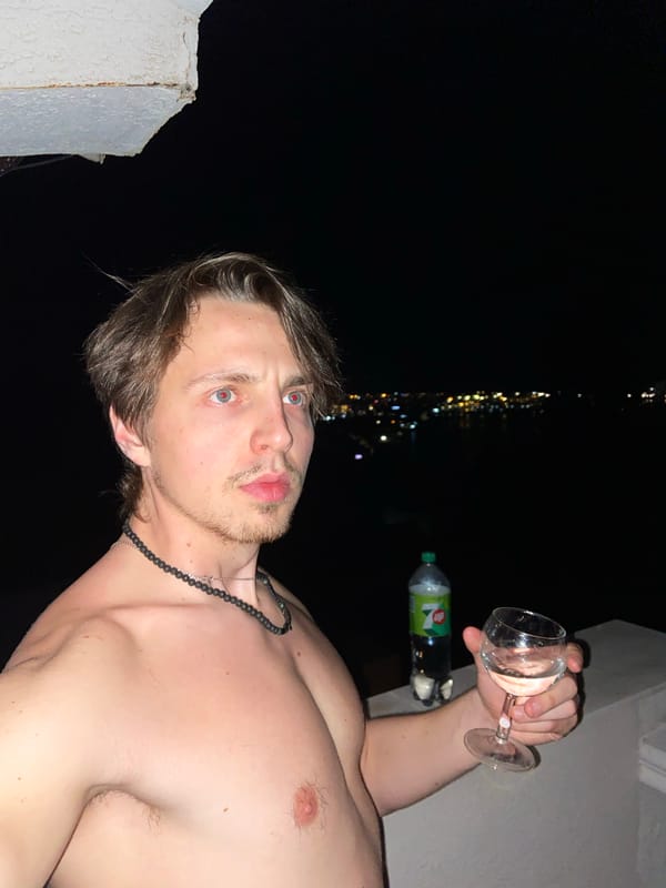 Man drinks wine on balcony overlooking Šušanj Montenegro