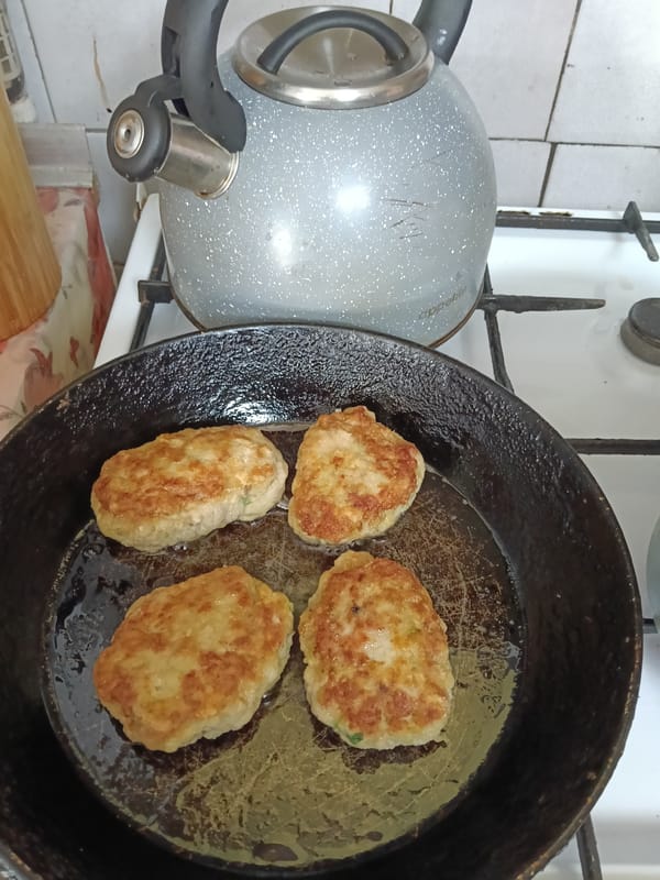 Cook prepares golden patties in cast-iron pan