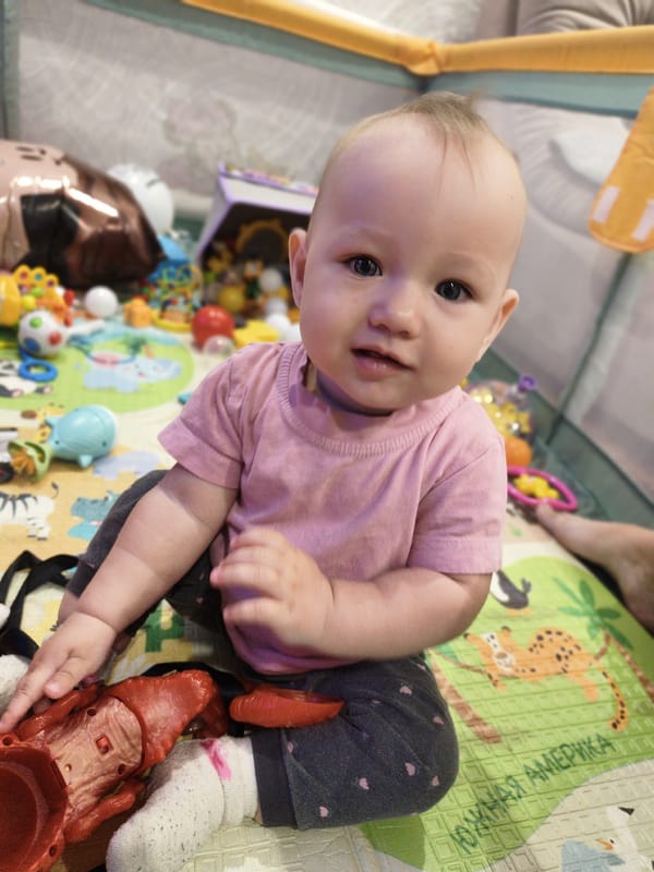 Baby plays with toys on colorful mat in Russia