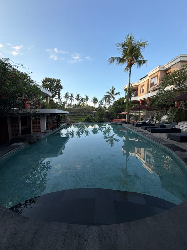 Swimming pool reflects buildings, palm trees in Peliatan, Indonesia