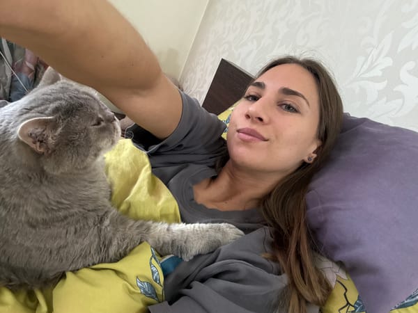 Woman and gray cat share quiet moment on bed in Zanevka