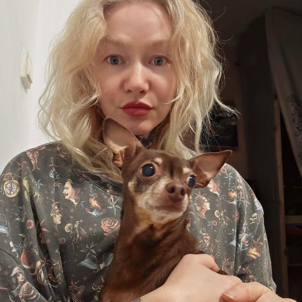 Person holds Chihuahua while wearing tattoo-print shirt in Saint Petersburg