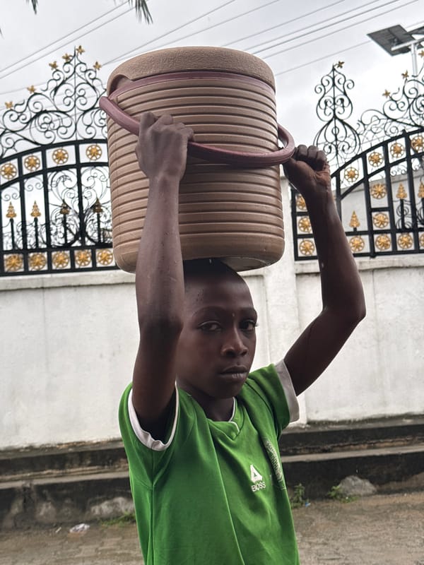 Children walk wet streets in Ado during overcast afternoon