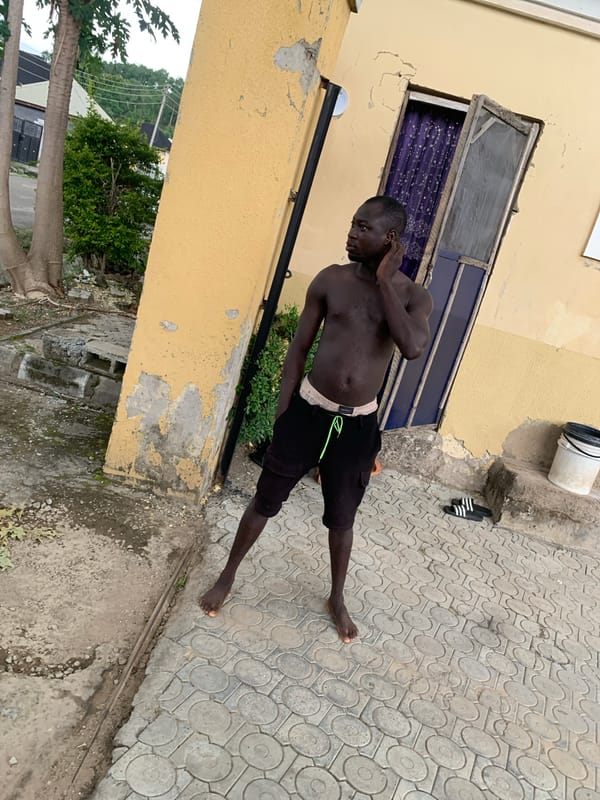 Casual afternoon activity outside a yellow building in Abuja