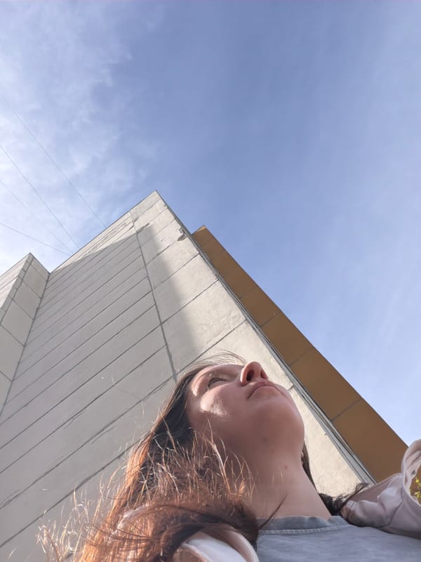 Woman gazes upward at building under clear skies in Staraya