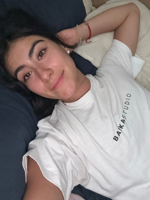 Woman rests on bed in Puebla wearing branded shirt