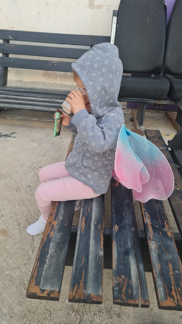Child in fairy wings rests on bench in Rishon LeZion