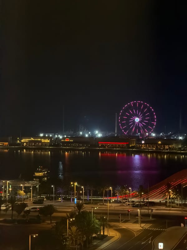 Ferris wheel and crescent moon over a lit Gulf waterfront