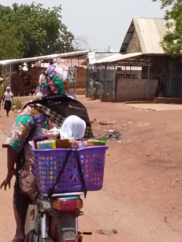 Woman and child travel by motorcycle in Dungu, Ghana