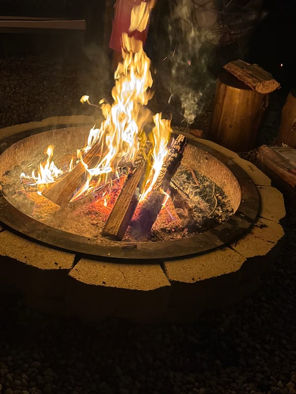 Late night outdoor gathering features fire pit, music, games