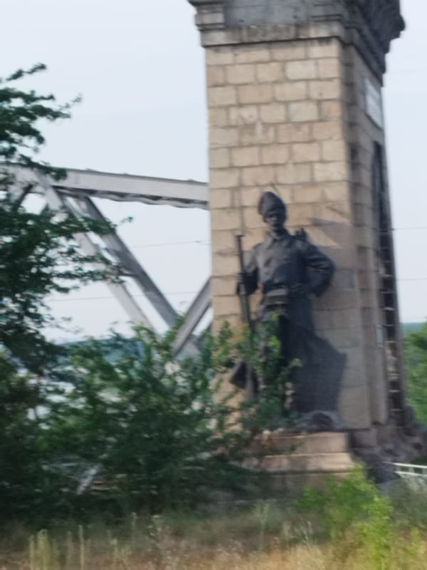 Danube crossing at Cernavodă: truss bridge, barges, and soldier statue