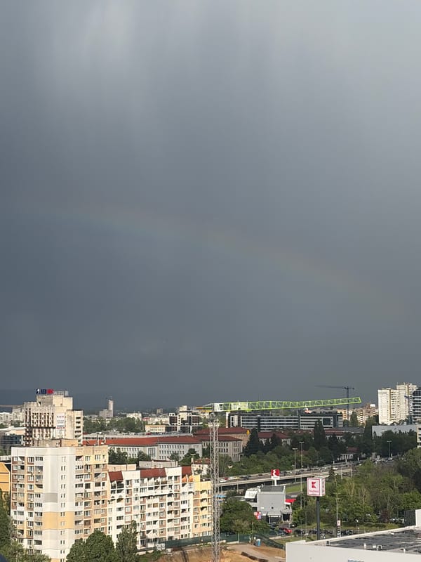 Rainbow appears over city during afternoon storm conditions