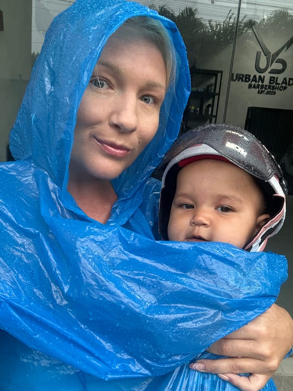 Woman and child shelter under poncho in North Kuta