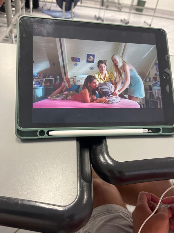 Tablet displays bedroom scene with three women, witness observes
