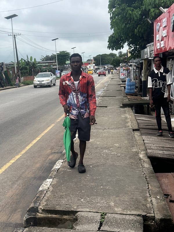 Wet morning street activity along a Badagry commercial strip