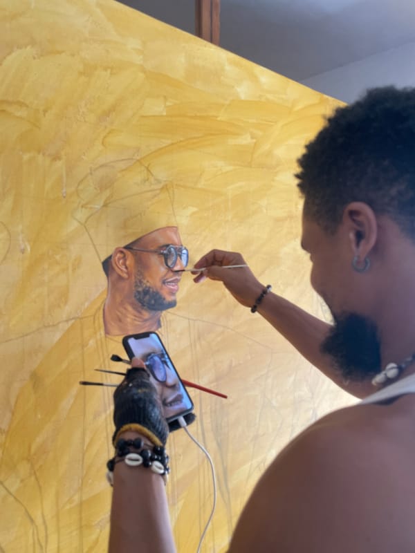 Artist paints bearded portrait on yellow canvas in Ado