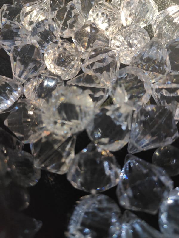 Clear faceted gemstones catch light on a dark surface