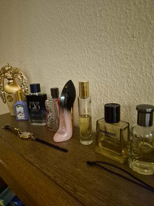 Perfume collection and accessories laid out on a wooden dresser