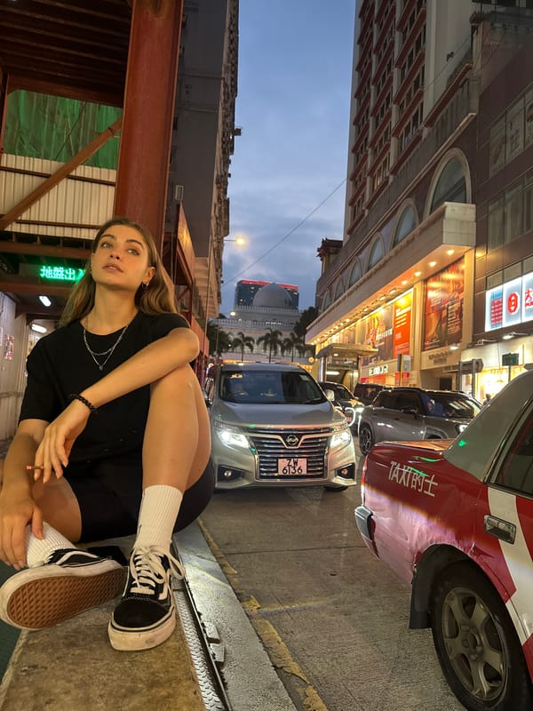 Woman sits on street ledge in Hong Kong nighttime scene