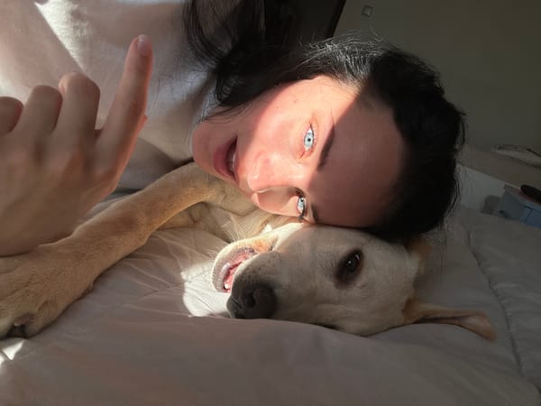 Woman rests in bed with light-colored dog companion