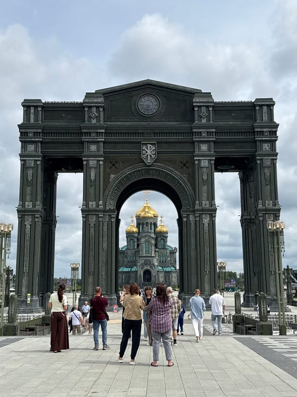 Ornate triumphal arch frames golden-domed cathedral in Russia