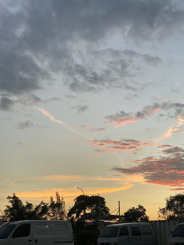 Dusk settles over a busy parking lot in Gambut Barat