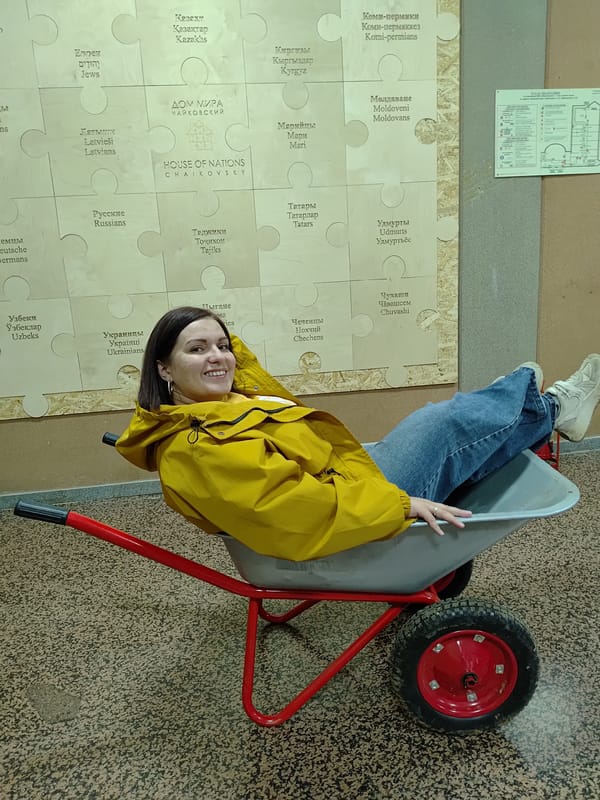 Women pose playfully with wheelbarrow at Markovskii cultural center