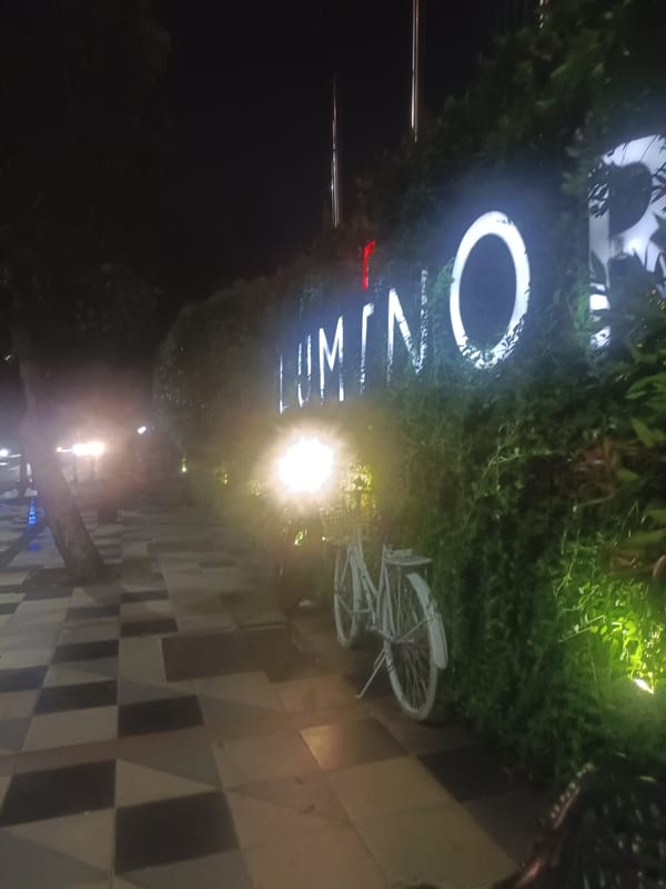 Nighttime street scene captured with illuminated LUMINO sign, bicycle