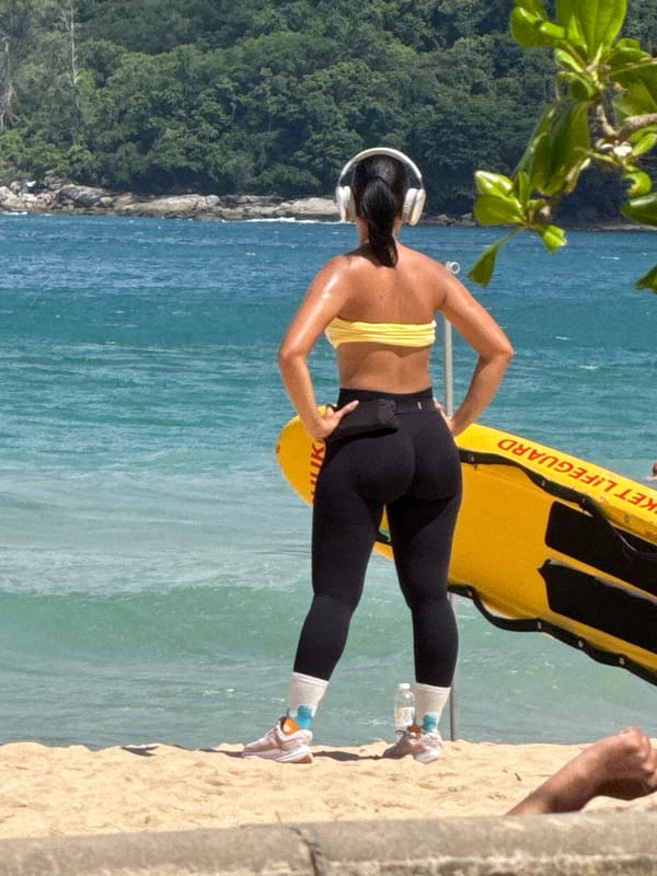 Beach morning in Rawai: scooters, shoreline hangout, paraglider overhead