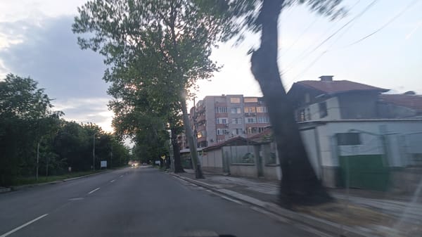 Vehicle travels tree-lined street in Aytos, Bulgaria