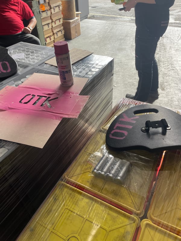 Workers spray paint pink markings on container in Bulgarian warehouse