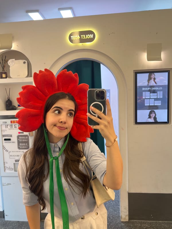 Woman takes selfie wearing red flower headpiece in Seoul photo booth