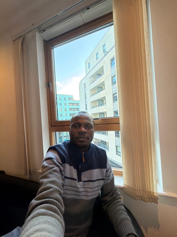 Man observed by window overlooking modern buildings in Leeds