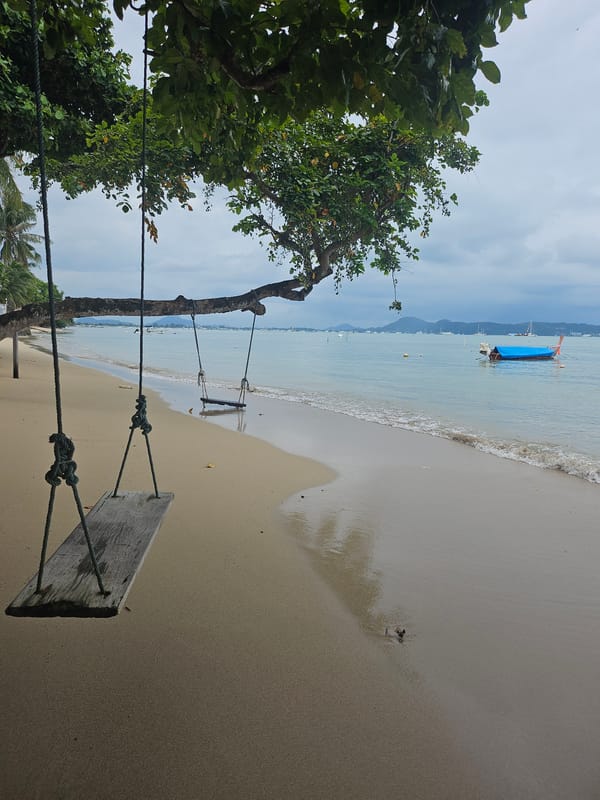 Low tide, overcast skies, and wooden swings at Rawai Beach