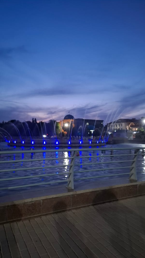 Shymkent park at dusk, fountains lit and evening setting in