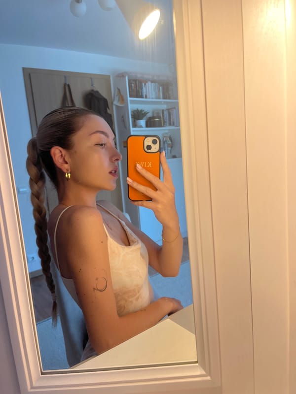 Woman takes multiple mirror selfies with personalized orange phone case