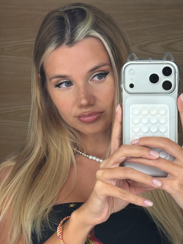 Selfie with cat-ear phone case against a wooden wall