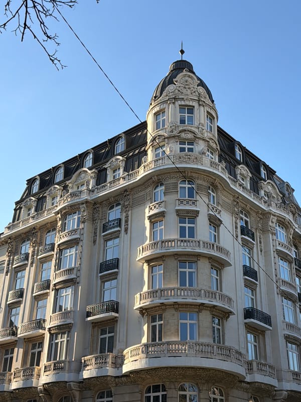 Ornate building and pink SUV documented in street scene