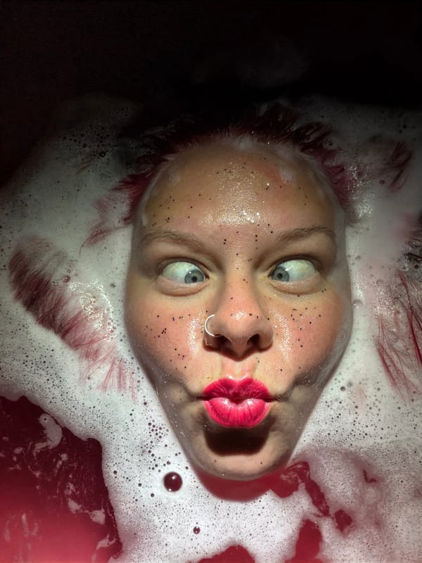 Person photographed partially submerged in red-tinted foamy water