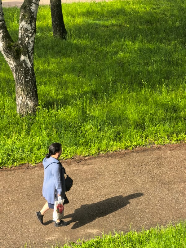 Woman walks through sunlit park in Sterlitamak, Russia