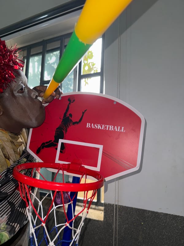 Person with face paint, crown poses under basketball hoop