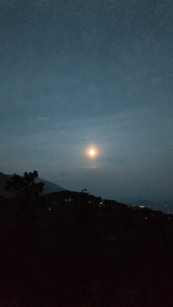 Bright moon observed over Dharamkot mountains during daylight hours