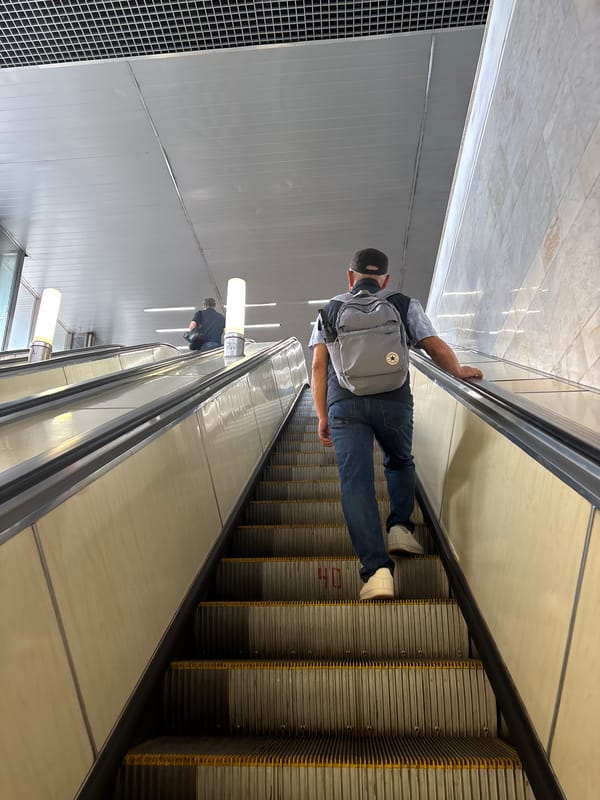 Escalator ride with a gray backpack and checkered shirt