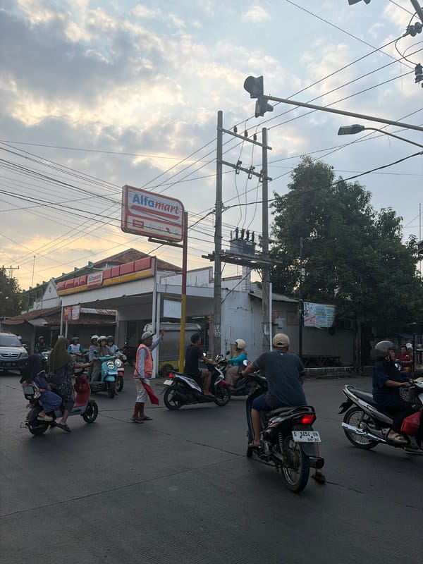 Street life at a Pekalongan junction — juice stalls, motorcycles, and big skies