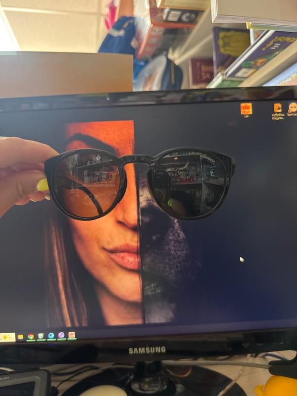 Sunglasses held up to a split-screen monitor at a Bulgaria desk